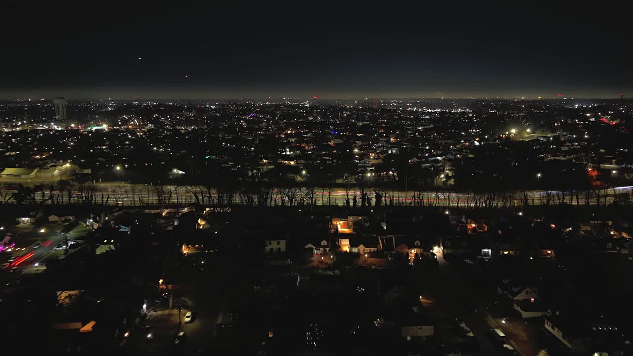 Hyperlapse aéreo sobre un barrio residencial de noche, lo suficientemente alto como para ver el horizonte con un cielo despejado en Valley Stream, NY. La cámara del dron se aleja desde la Southern State Parkway