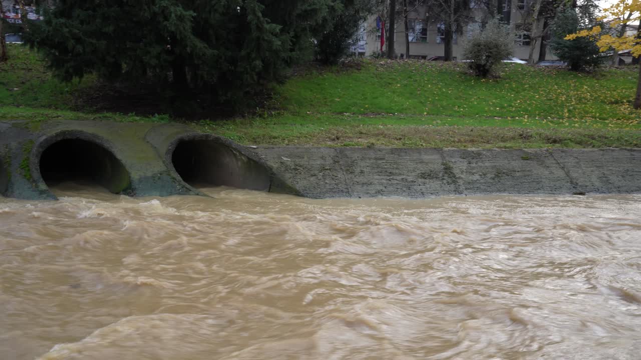 Turbid, polluted water flows from drainpipes into city river of Lana after torrential rain with risk of flooding in Tirana