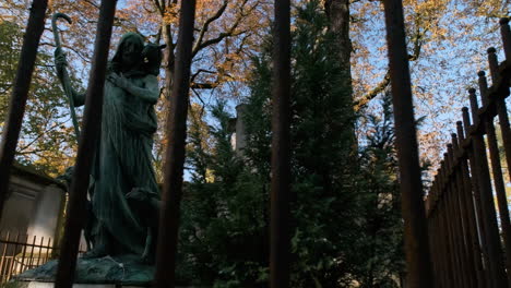 toma lateral de una hermosa estatua tras las rejas en el cementerio pere lachaise