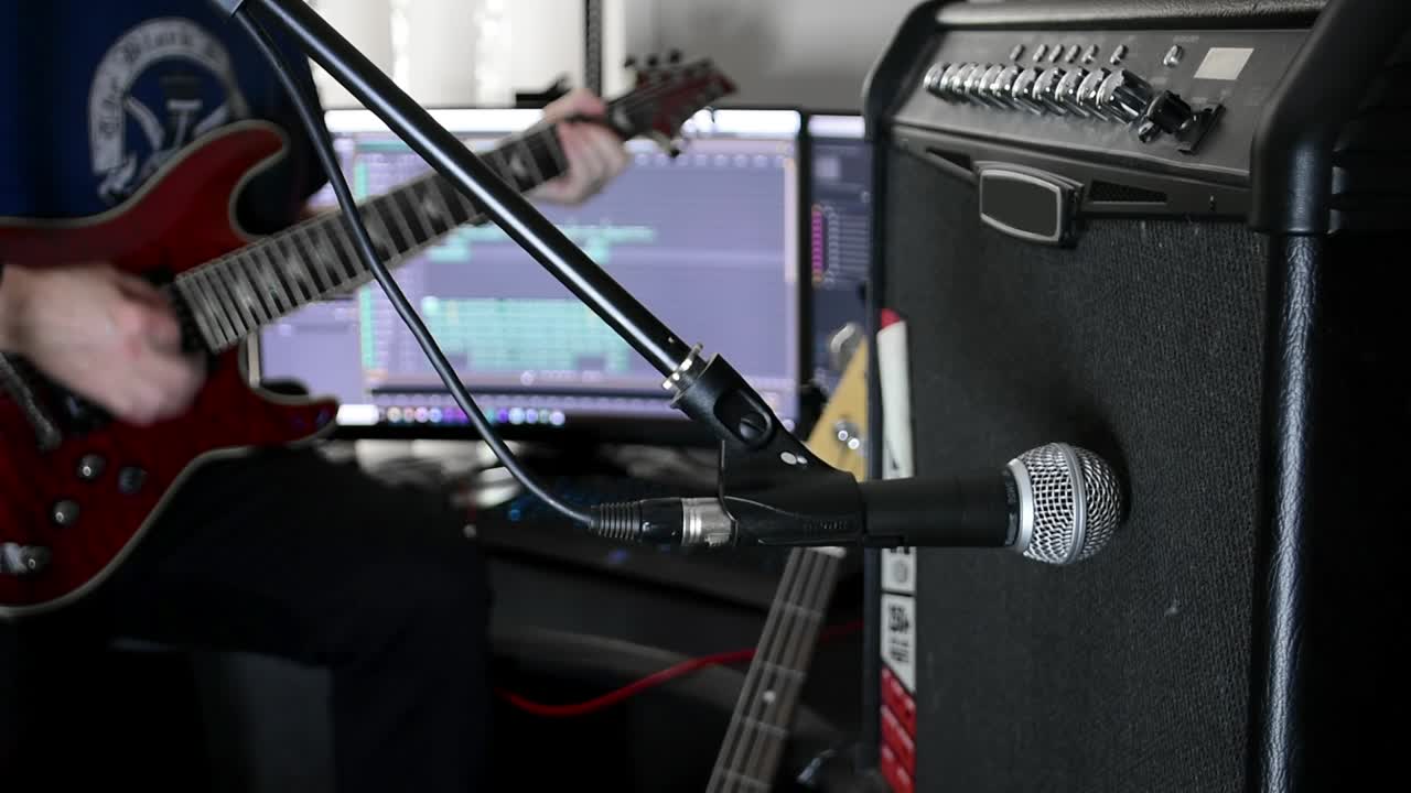 전경에 앰프와 마이크가 있는 기타를 연주하는 음악가, 컴퓨터에서 녹음