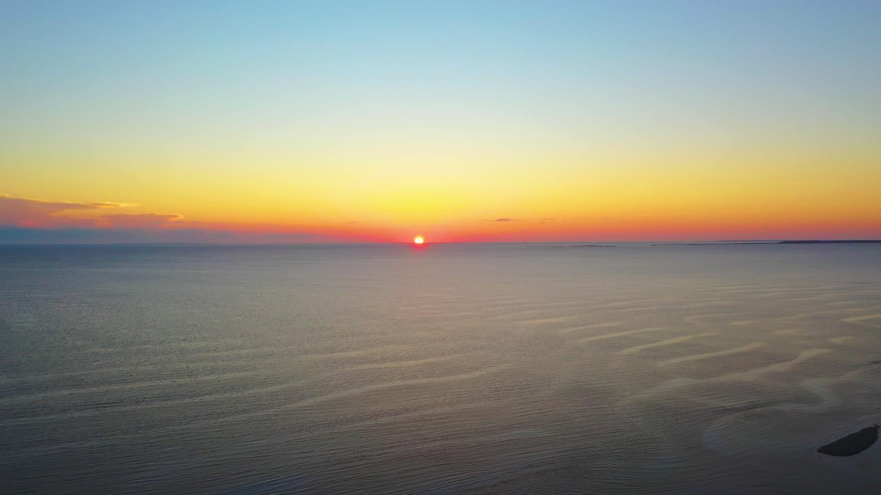 hermosa puesta de sol en el océano imágenes aéreas de drones del sol tocando el horizonte y el colorido cielo amarillo, rojo y azul