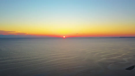 Hermosa-Puesta-De-Sol-En-El-Océano-Imágenes-Aéreas-De-Drones-Del-Sol-Tocando-El-Horizonte-Y-El-Colorido-Cielo-Amarillo,-Rojo-Y-Azul