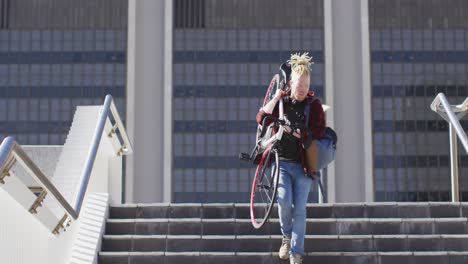 Thoughtful-albino-african-american-man-with-dreadlocks-going-down-stairs-with-bike