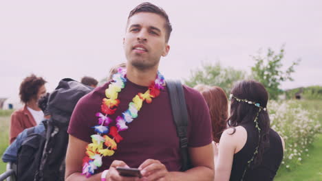 hombre con amigos en un festival de música usando el teléfono móvil para organizar una reunión