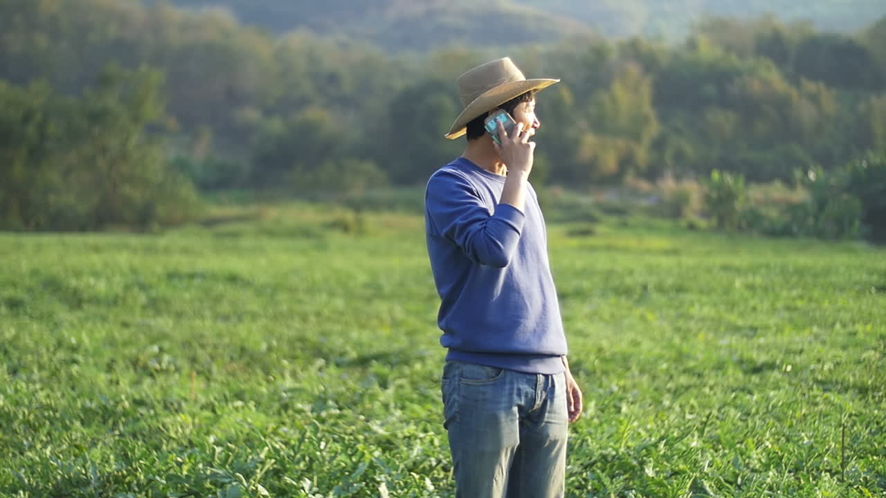 Asian Farmer In A Field Talking On Phone