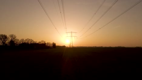 dolly motion under high voltage wires during sunset, silhouette of electric tower