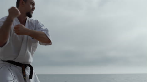 Sportlicher-Mann,-Der-Am-Strand-Karate-Kämpfe-übt.-Bärtiger-Sportler-Trainiert-Im-Freien