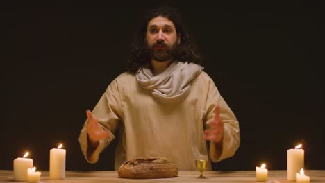 fotografía de estudio de un hombre vestido con túnicas que representan a la figura de jesucristo predicando y partiendo el pan