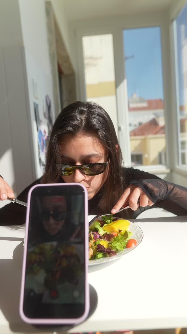 Young Woman in Sunglasses Eating Salad While Recording with Smartphone