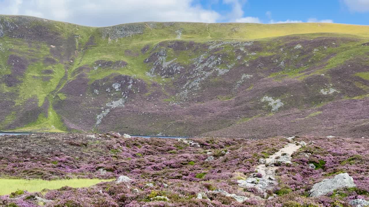 Camera pans across Loch Brandy, showing heather hills, rocky slopes, and a tranquil lake