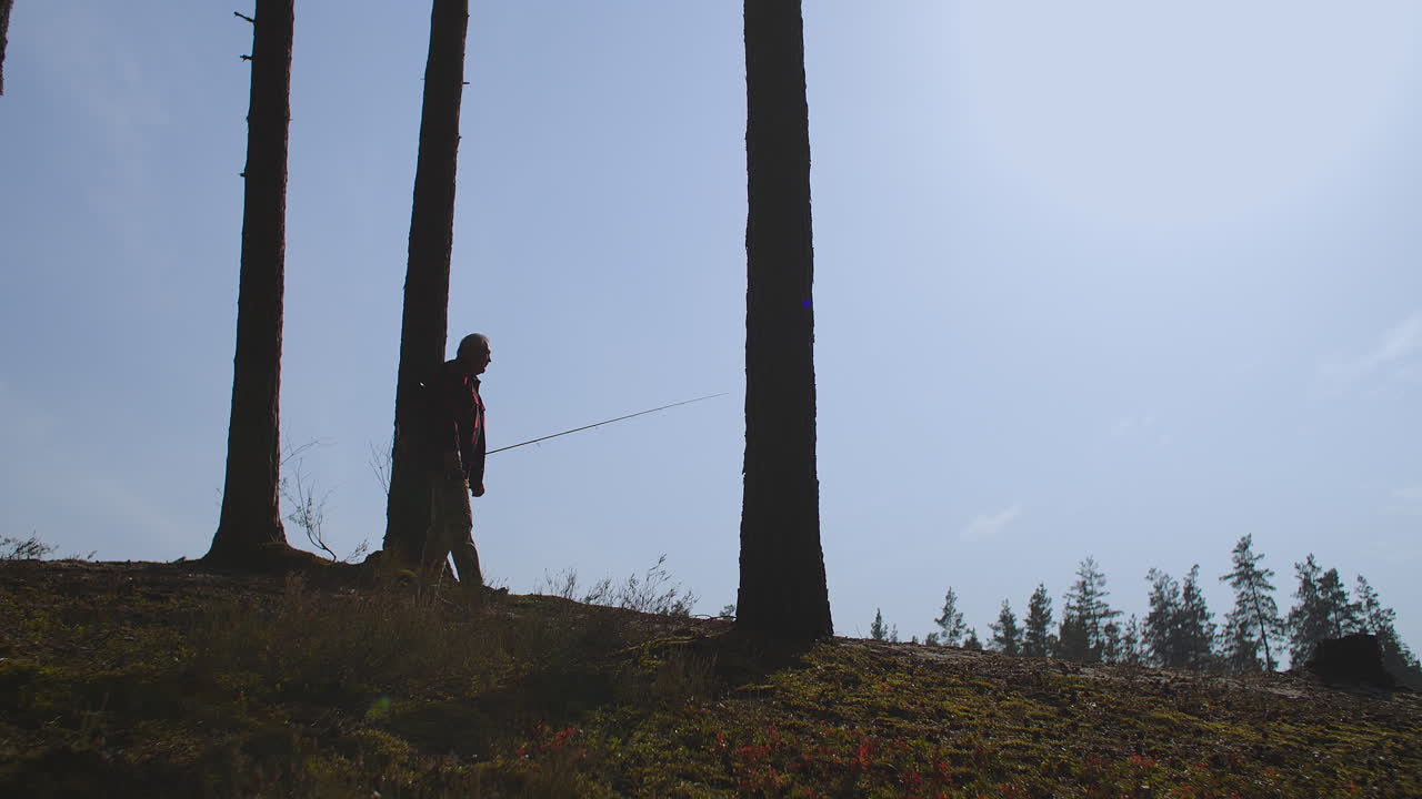 solo pescador con la vara en la mano está caminando en la naturaleza silueta vista contra el cielo azul disparo en cámara lenta