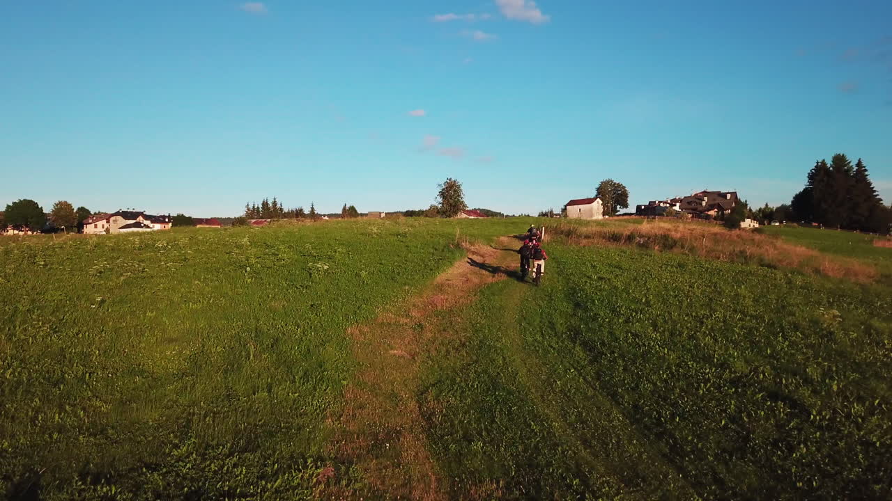 Ripresa aerea in movimento di tre mountain biker che salgono verso un piccolo villaggio di campagna in Italia.