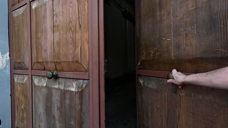 hand opening a large wooden door