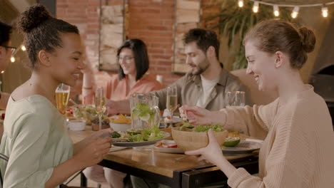 young woman serves salad to an youg female