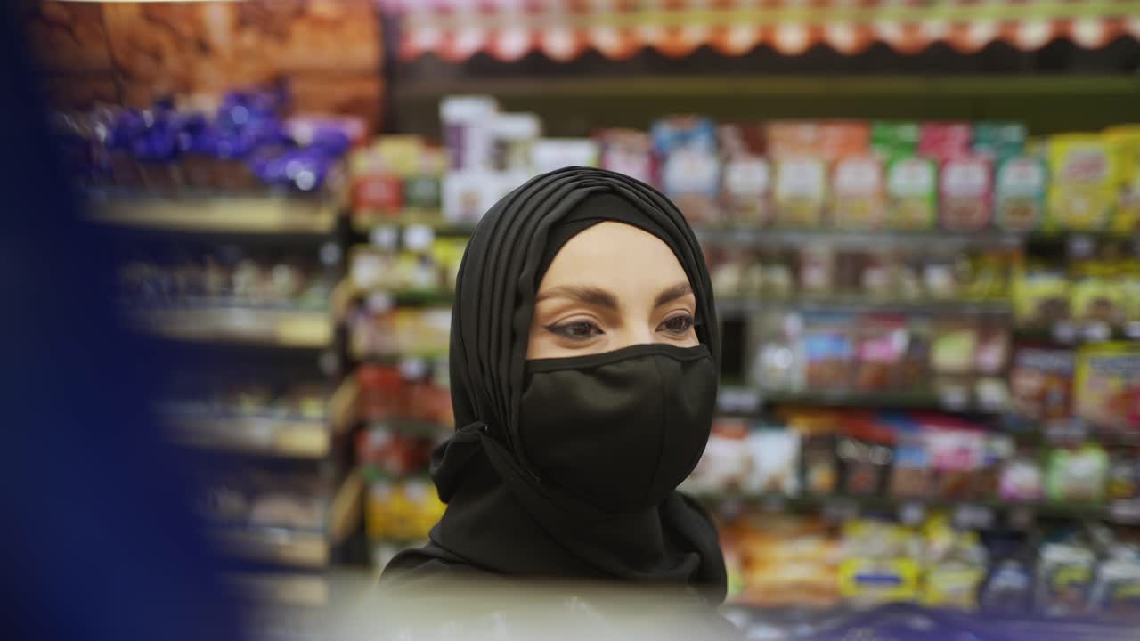 mujer con hijab y máscara toma el producto del estante, imágenes del interior