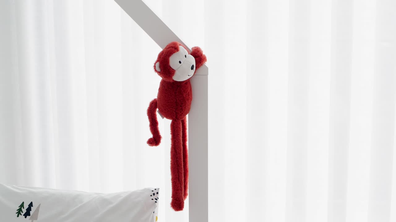 soft red monkey toy wrapped on frame in bright children’s bedroom