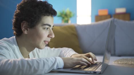 un adolescente está enviando mensajes de texto románticos y afectuosos con su novia desde la computadora portátil en casa.
