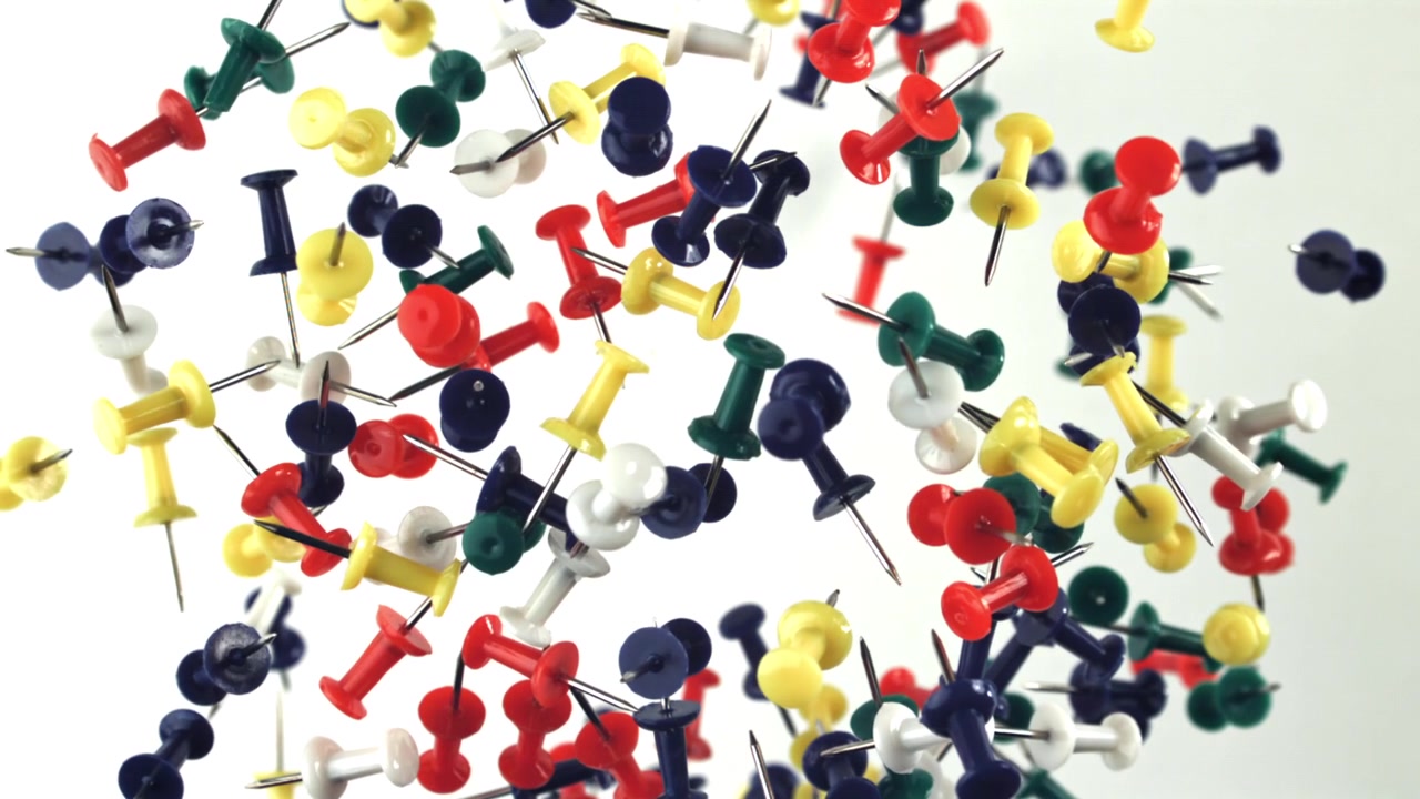 Many Colorful Pushpins Floating and Falling in Slow Motion