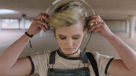 portrait-of-cool-young-woman-puts-on-headphones-listening-to-music-alternative-grunge-trendy