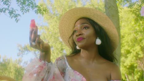 Black-Woman-pointing-eating-watermelon-on-picnic-in-park