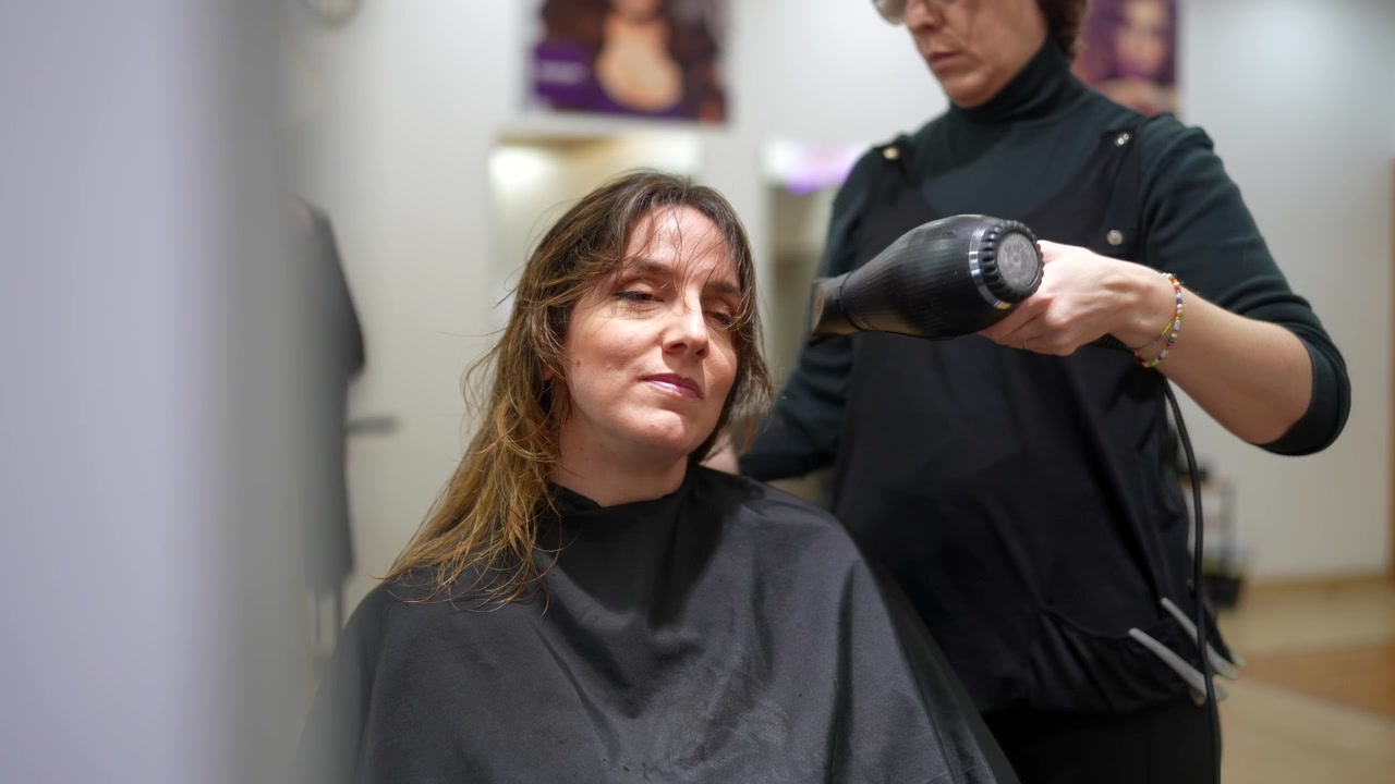 Parrucchiere che asciuga i capelli del cliente in un salone professionale