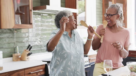 Happy-senior-african-american-female-friends-preparing-meal,-singing-and-high-fiving,-slow-motion