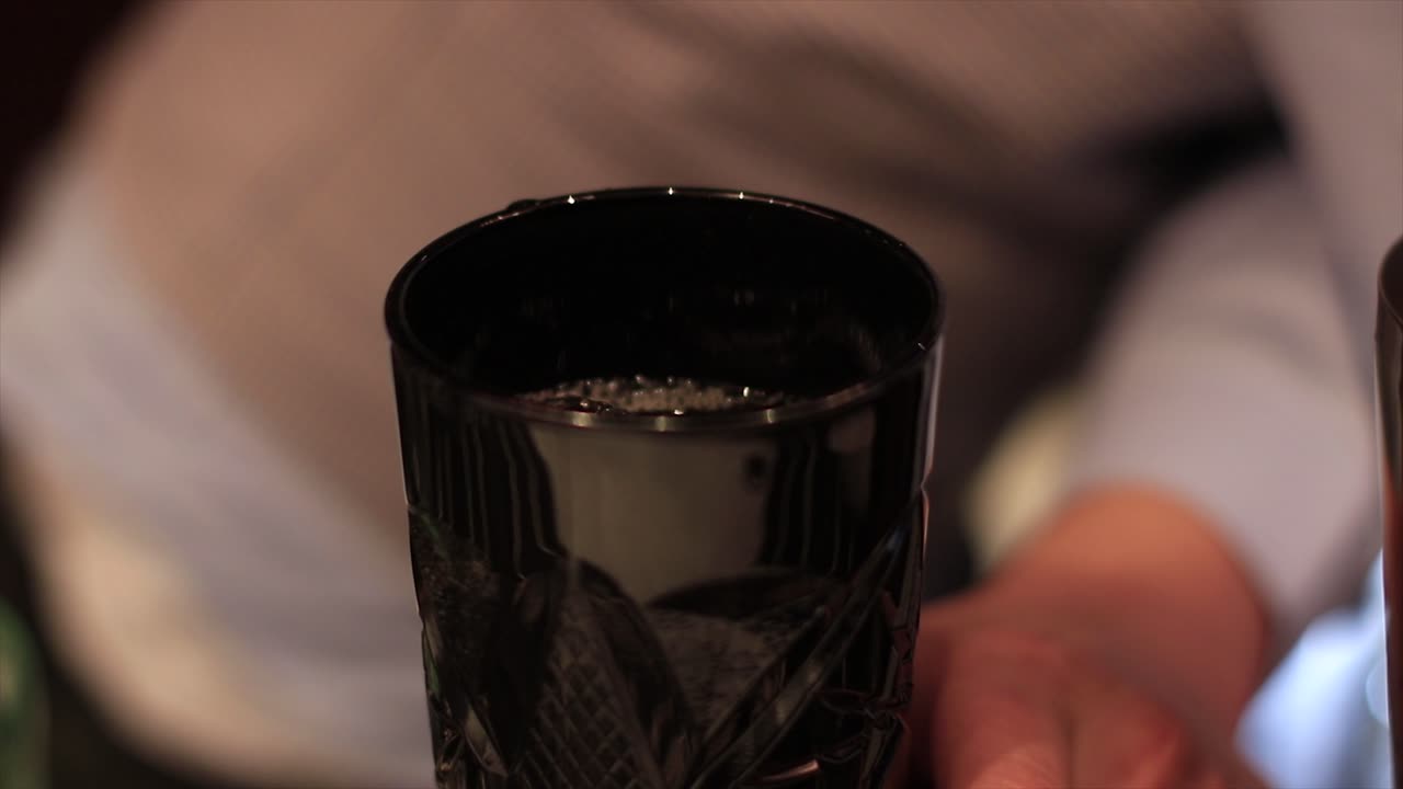 Bartender making a cocktail and adding ice in the end. Cocktail creation.