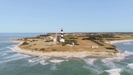 aerial view of a lighthouse on a coastal peninsula with crashing waves