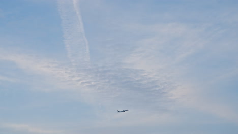 An-airplane-departs-into-a-beautiful-blue-sky-with-sunlit-clouds-in-the-morning-lights