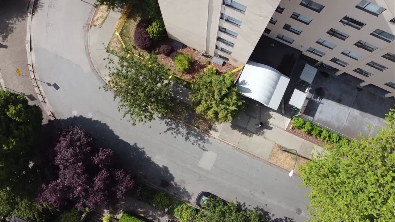 2-2개의 꼬인 나선형 공중 조감도는 10층 높이의 아파트 건물을 가로질러 빅토리아 시대 주거용 단독 주택을 통해 화창한 여름날 무성한 푸른 나무가 있는 막다른 곡선 도로 위에 있습니다.