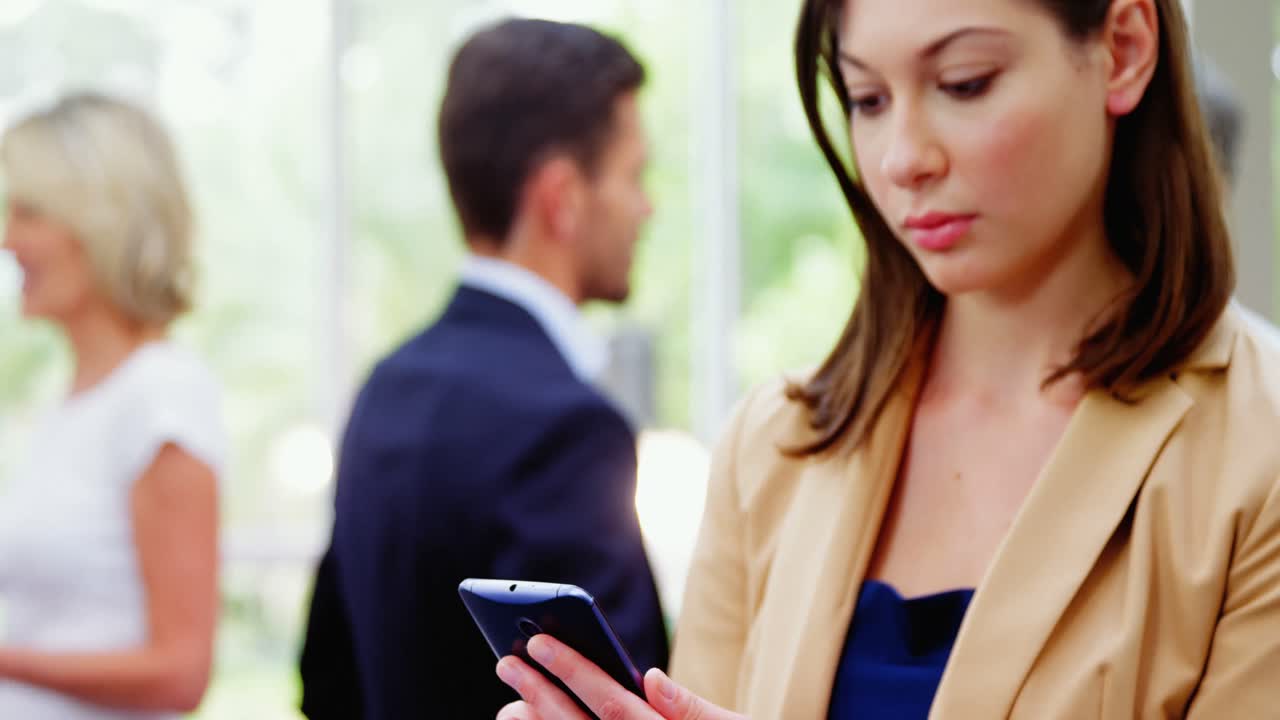 Female business executive text messaging on mobile phone