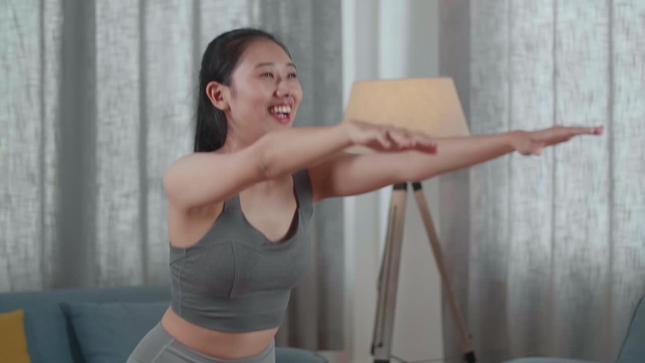 스포츠 옷을 입은 젊은 아시아 운동선수 여성의 근접 초상화. 집에서 매트에 이 운동 스을 하고 있다.