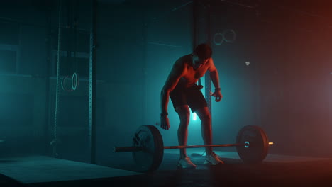 muscular fitness man doing push a barbell over his head in modern fitness center. functional training. snatch exercise. slow motion color led light saturated bright colors