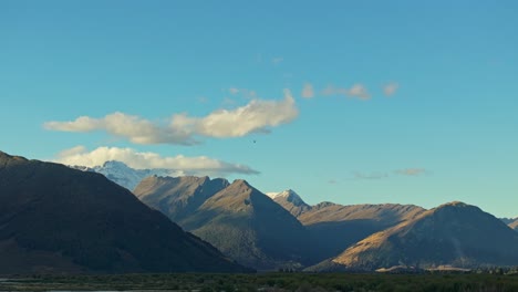 wispy clouds sit calmly above sunlight on mountain peak tops in glenorchy