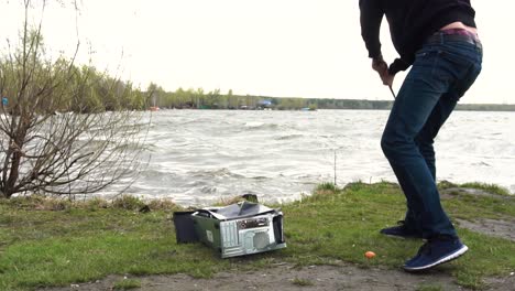 angry man destroying a computer by the river