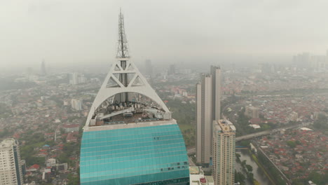 Nahaufnahme-Der-Kreisenden-Luftaufnahme-Der-Antenne-Des-Wolkenkratzers-Wisma-46-In-Jakarta,-Indonesien-An-Einem-Bewölkten-Tag