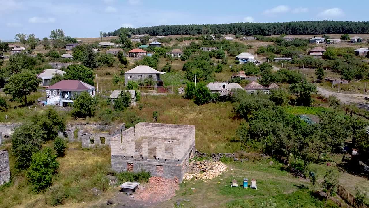 Discover a serene, abandoned village nestled in lush greenery. Explore the remnants of homes and nature reclaiming the land under a clear blue sky