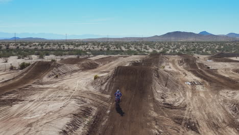 Motorcycles-flying-over-dirt-jumps-towards-the-drone-camera-on-an-off-road-track