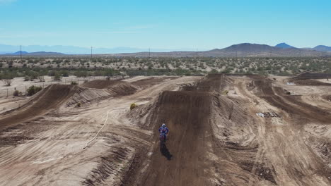 motocicletas que vuelan sobre saltos de tierra hacia la cámara de drones en una pista todoterreno