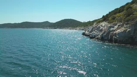 reveal drone shot next to a rocky shore in the aegean sea