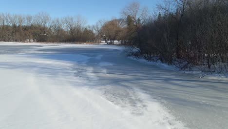 Lake-at-the-park-surrounded-by-trees-on-a-winter-afternoon-completly-covered-in-snow