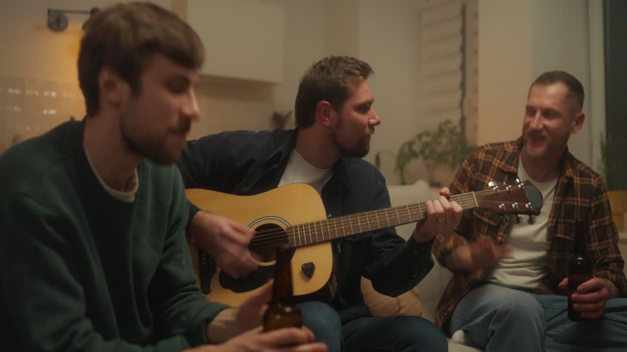 Amici che suonano la chitarra e bevono birra