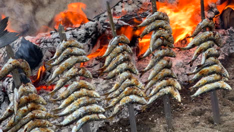 Sardinas-Tradicionales-Españolas-Espetos-Pescado-Asado-En-La-Playa-Sobre-Fuego-En-Brochetas-De-Metal-En-Marbella-Málaga-España,-Deliciosos-Mariscos,-Toma-De-4k