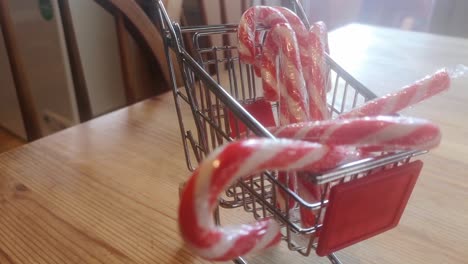 pequeño carrito de compras lleno de bastones de caramelo de navidad concepto de entrega a domicilio idea de cocina dolly izquierda