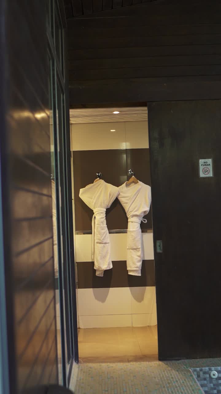 Cozy luxury hotel room featuring two bathrobes hanging on hooks in a modern, well lit bathroom, creating a welcoming and relaxing atmosphere for guests