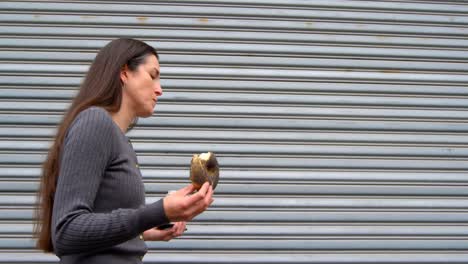 mujer hermosa que tiene rosquillas mientras camina en la ciudad 4k