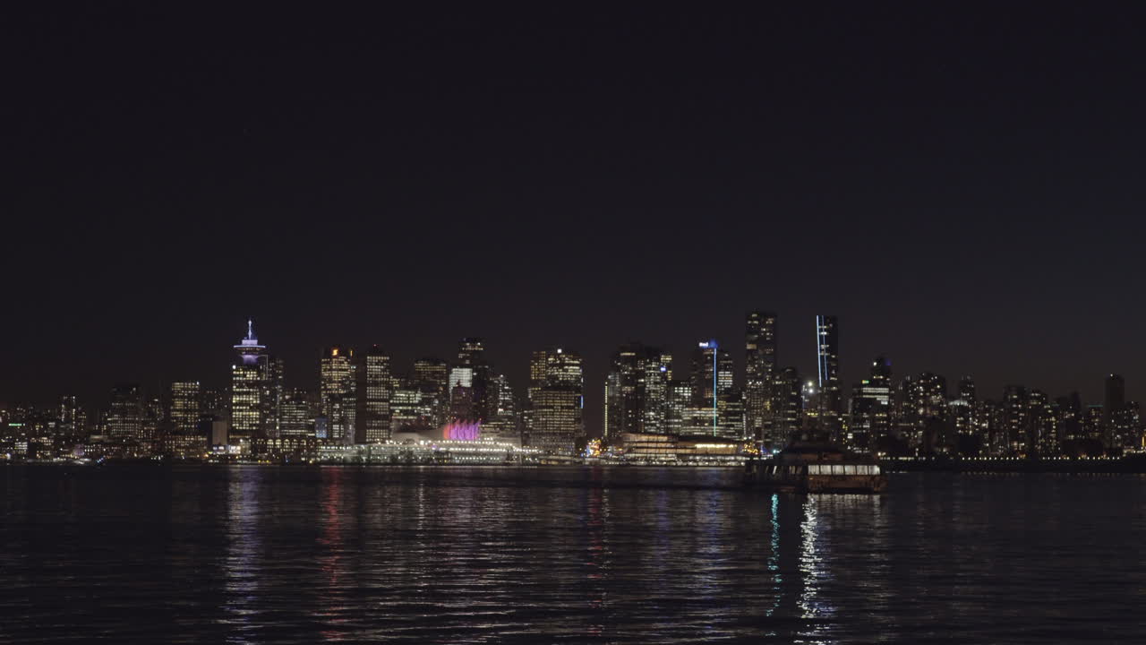 바다 버스가 론스데일 케이에 다가오고, 밤에 밴쿠버 스카이라인이 배경입니다.