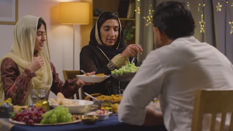 muslim muslim family sitting around table at home eating meal to celebrate eid 2