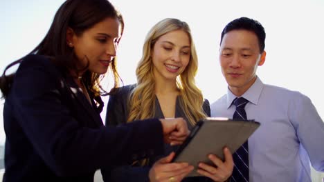 multi ethnic business consultants using touchscreen on rooftop