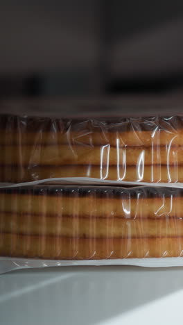 una mano femenina tomando galletas de pastel envasadas de un estante de la tienda. filmado con una cámara portátil, capturando la acción de seleccionar artículos de panadería en un entorno minorista